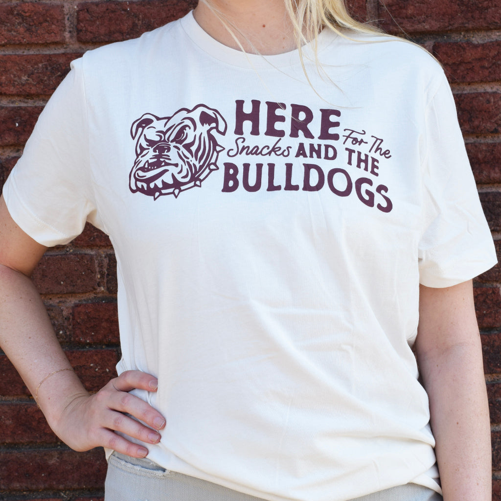 white tee shirt with wording here of the snacks and the bulldogs