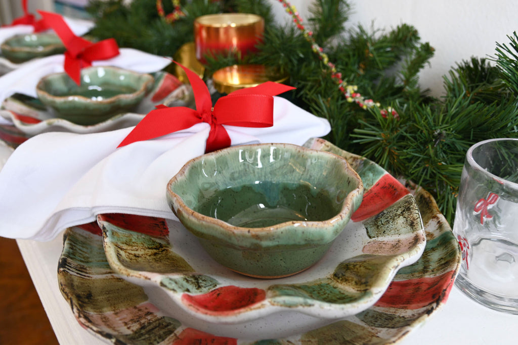 Decorative ceramic dish with green glaze on a festive table setting with Christmas decorations.