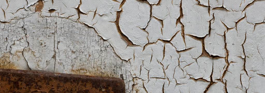image of cracked white paint due to age and rusting on metal